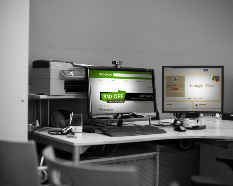 two monitors open to groupon and google offers