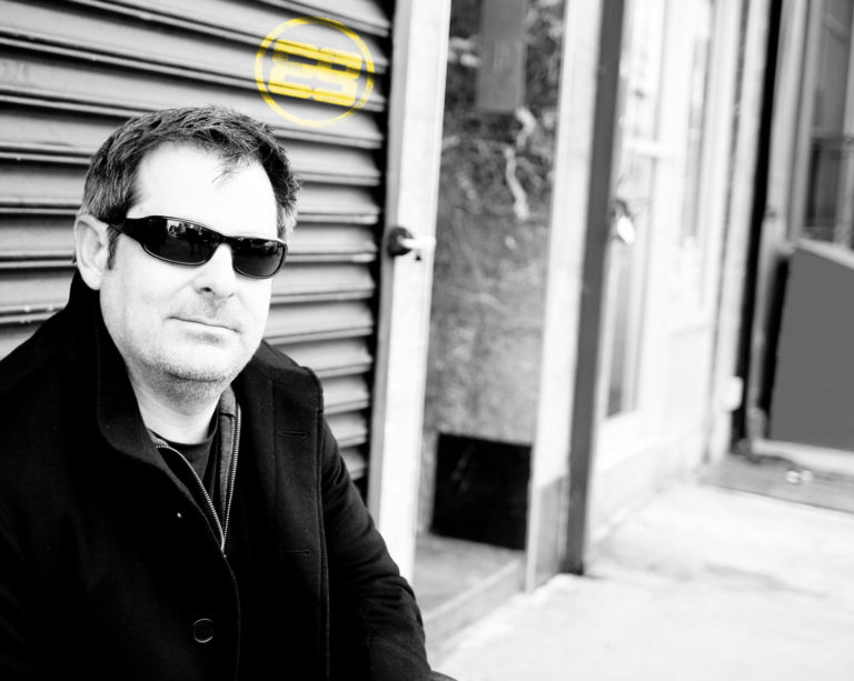 Conrad, founder of e9digital, with glasses posing in front of garage