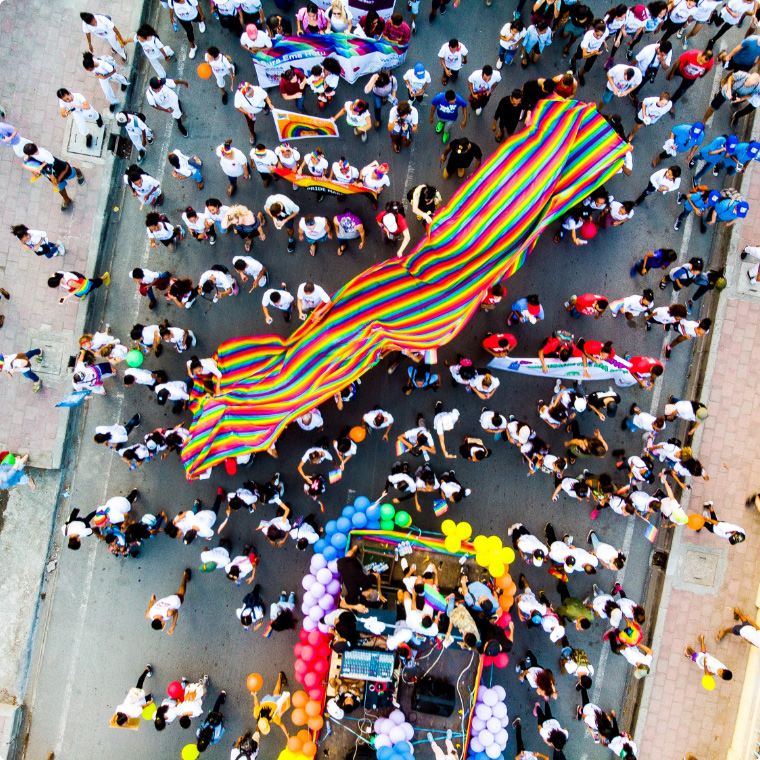 people with rainbow items marching down street